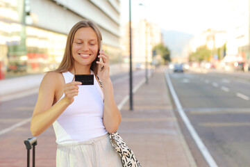 Beautiful young smiling woman with smartphone and credit card by the airport. Happy girl with...