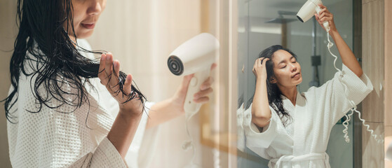 Asian Woman Drying And Styling Hair With Hairdryer in Bathroom, Beautiful Happy Female Standing in...