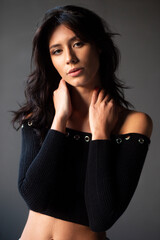 Closeup front of a cheerful brunette young woman posing in studio portrait against grey background.