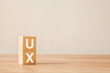 ユーザーエクスペリエンス。UX。木製のブロックに描かれているUXの文字。木製のテーブルの背景。