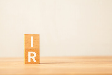 投資家向け広報。IR。インベスター・リレーションズ。木製のブロックに描かれているIRの文字。木製のテーブルの背景。