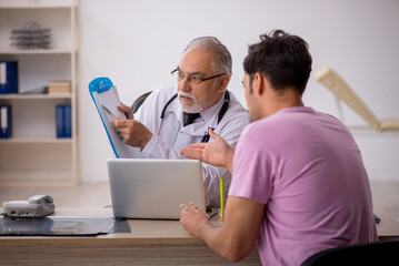 Fototapeta premium Young male patient visiting old male doctor