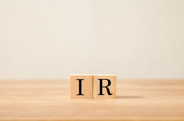 投資家向け広報。IR。インベスター・リレーションズ。木製のブロックに描かれているIRの文字。木製のテーブルの背景。