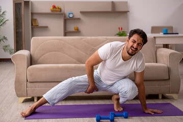 Fototapeta premium Young man doing sport exercises at home
