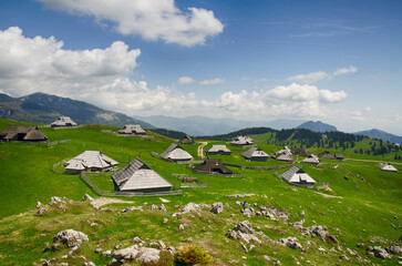 Fototapeta na wymiar Velika Planina or Big Pasture Plateau in the Kamnik Alps, Slovenia. Mountain cottage hut or house on green hill. Alpine meadow landscape. Eco farming