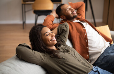 Obraz premium Happy African American Couple Relaxing Sitting On Sofa At Home