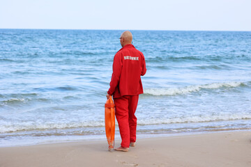 Ratownik na plaży podczas patrolowania brzegu wody.  - obrazy, fototapety, plakaty