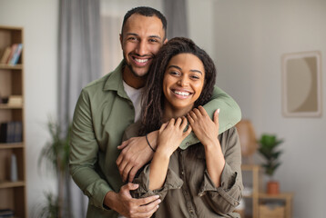 Joyful African American Husband Hugging Wife Standing At Home