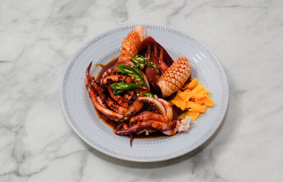 Squid boiled in spiced soy sauce on bright background.
