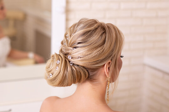 Young beautiful bride with blonde wedding hairstyle and makeup in hairdressing salon
