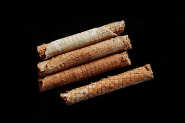 wafer rolls with condensed milk on a black background