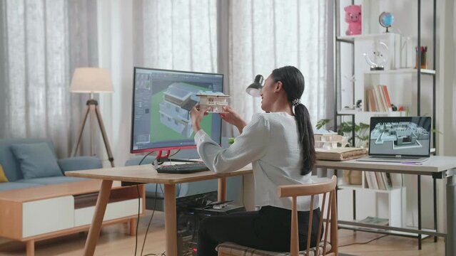 Asian Woman Engineer Holding And Looking At The Small House Model With Solar Panel While Designing House On A Desktop At Home. Cyber Games House Design And Decoration
