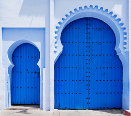 Two blue painted doors on white stone building.
Islamic architecture.