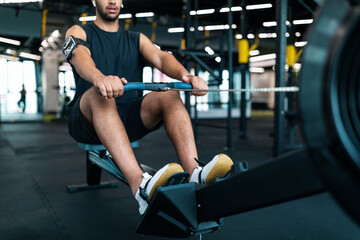 Fototapeta na wymiar Motivated Black Male Athlete Training On Rowing Machine At Gym