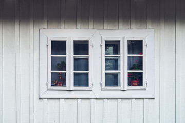 Obraz premium A detail of a white window against a white facade made of wooden planks. Country window