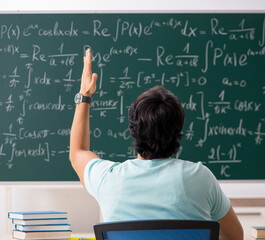 Young male student mathematician in front of chalkboard