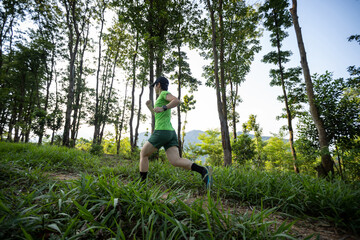Woman trail runner running at sunrise tropical forest mountain peak