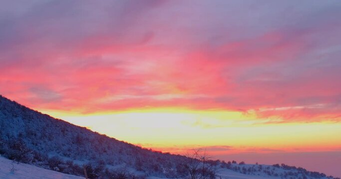 Colorful sunset sky above the snowy mountains, slow motion