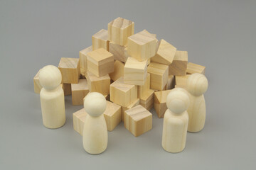 Construction, teamwork and creating concept. Wooden people figures and many  cubes on gray background. 