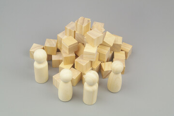 Construction, teamwork and creating concept. Wooden people figures and many  cubes on gray background. 