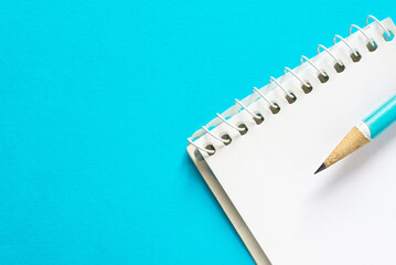 stationery concept, top view of notebook and pencil on blue background