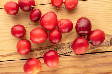 Several organic juicy cherry plums on a wooden table, close-up, top view.