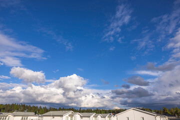 Beautiful view of blue sky with thunder clouds over roofs of village houses. Sweden.