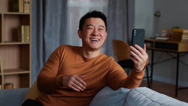 Happy Middle Aged Asian Man Video Chatting With Family Or Friends Via Cellphone App, Slow Motion, Free Space