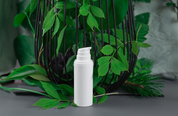 a bottle with a white dispenser stands near live leaves. High quality photo