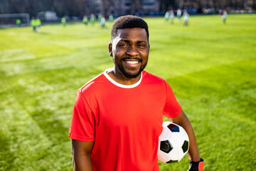 happy multicultural hispanic soccer player smiling and wear red sporty suit outdoor sunny day