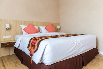 Fototapeta na wymiar White bed with double pillows, interior decorated with wood and Thai pattern.