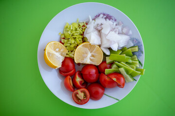 A plate of fresh vegetables on a green background.