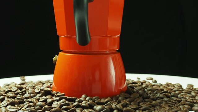 Classic vintage orange moka pot rotating itself on black background, Italian espresso maker homemade coffee preparing for making fresh coffee from beans.