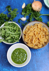 Pasta pesto ingredients on a table. Close up photo of pasta, mozzarella, zucchini, parsley, garlic, onion and pesto sauce. Balanced menu concept. 