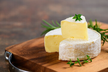 Sliced Camembert Cheese with thyme on wood plate.