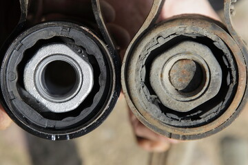 New and old defective silent blocks with metall sleeves close up. Car suspension arm diagnostic service