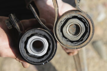 New and old torn silent blocks with metall sleeves close up. Car suspension arm repair