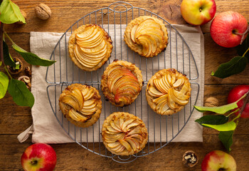 Mini Apple pie tartlets with walnut on wooden table. Delicious dessert for autumn winter dinner.Top...