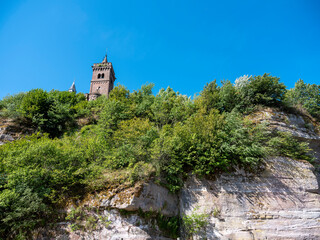 Fototapeta na wymiar church tower under blue sky on rock of dabo in french vosges mountains