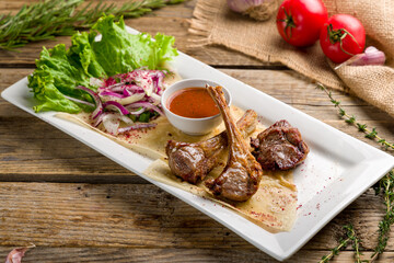 Rack of lamb with tomato sauce with red onion on old wooden table