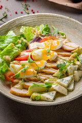 Cobb salad with chicken, egg and blue cheese on a plate on brown table vertical macro close up