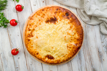 Ossetian pie with cheese on white wooden table