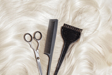 Scissors, comb and brush on blonde hair. Professional barber tools background. Hairdresser salon...