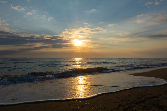 Sun shining through the clouds for a magical sunrise over the calm sea © raresb