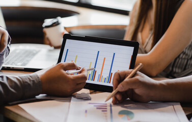 Modern business people, graphs and charts displayed on touchpad screen in business idea meeting and teamwork.