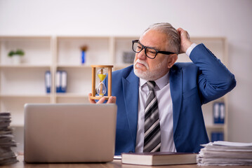 Fototapeta premium Old male employee in time management concept