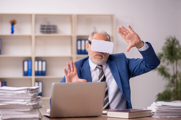 Aged male employee wearing virtual glasses in the office