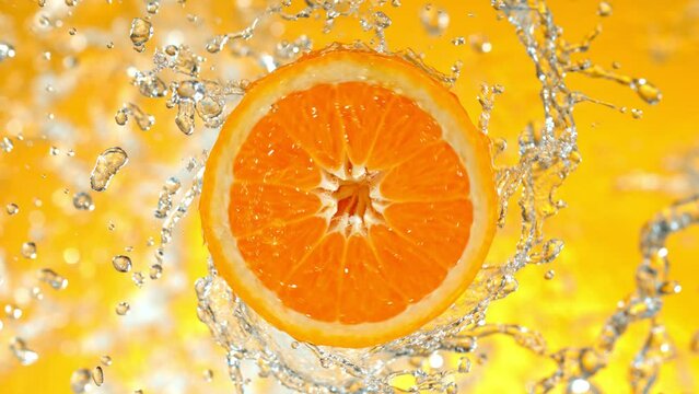 Super Slow Motion Shot of Rotating Fresh Orange Slice and Splashing Water at 1000fps.