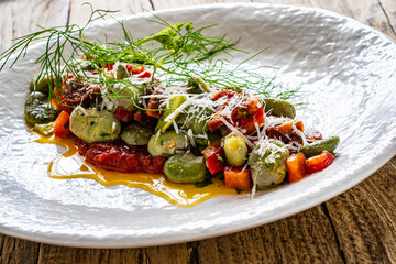 Broad beans salad in tomato sauce with chorizo, parmesan, garlic, pepper and dill on wooden table
