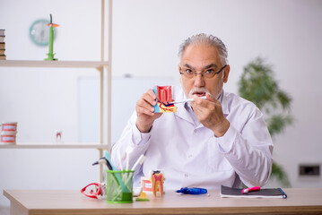 Old male dentist working in the clinic